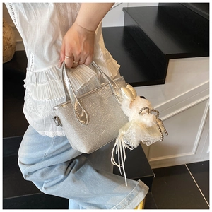 Detail of silver sequin handbag with cute white plush poodle pendant and leather handle