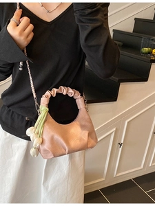Pink dumpling bag with metal chain and tulip charm accessory shown on model