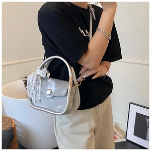 Silver square crossbody bag with metallic texture, metal handle and lace bow detail