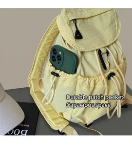 Detail shot of the side drawstring pocket on a beige nylon backpack holding a smartphone