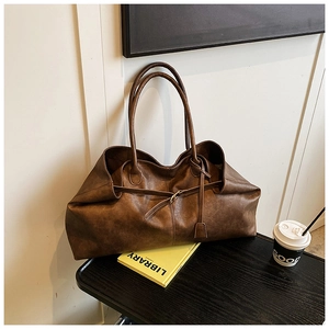 Close-up of vintage brown leather tote bag with retro buckle and grainy leather texture