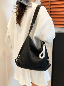 Sac bandoulière noir minimaliste style croissant avec large sangle et étiquette blanche