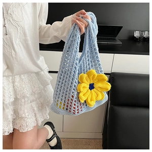 Close-up of light blue hollow knit bag featuring a large yellow crochet flower detail