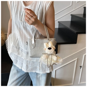 Detail of silver glitter handbag with cute white plush puppy pendant and metal D-rings