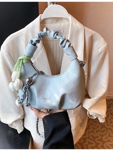 Light blue crescent handbag with pleated handle and floral chain charm shown on outfit