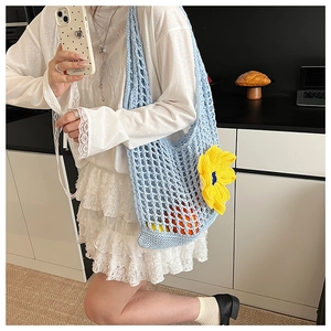 Detail of light blue crochet tote with yellow floral accent showing mesh texture and capacity