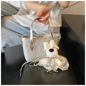 Silver glitter tote bag detail featuring a cute white plush puppy charm on handle