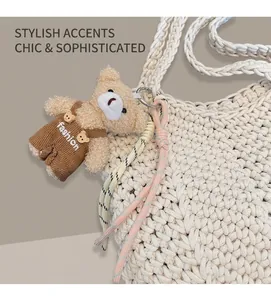 Detailed close-up of a plush bear charm with woven ropes on a beige braided handbag