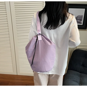 Detail of a light purple drawstring bucket bag in water-repellent nylon on a model