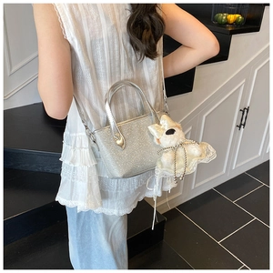 Close-up of shiny silver glitter handbag with a cute plush dog charm on shoulder