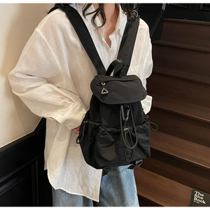 Dettaglio dello zaino in nylon nero con coulisse, patta e fibbie di utilità