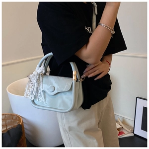 Detail of light blue crossbody bag with marble pattern and white lace bow accessory