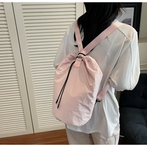 Detail view of pink drawstring bucket bag worn over shoulder in casual indoor setting