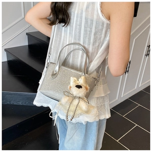 Detail of silver sequin mini tote bag with cute bear charm worn on the shoulder