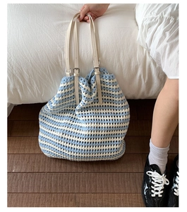 Detail of blue and white striped crochet tote with adjustable beige leather straps