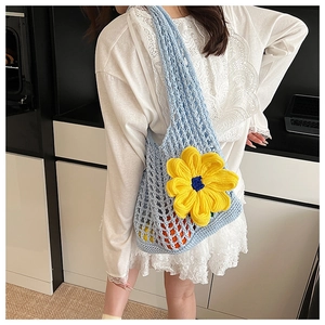 Close-up of light blue hollow knit beach bag with a bright yellow sunflower detail