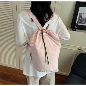 Detail of pink nylon drawstring bag showing lightweight fabric texture and black cord closure