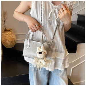 Silver sequin handbag with plush puppy charm shown on model in a modern lifestyle setting