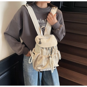 Dettaglio dello zaino in nylon bianco crema con coulisse laterali e moschettone decorativo