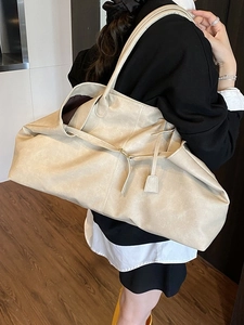 Large cream tote bag with leather texture and shoulder strap worn by a model