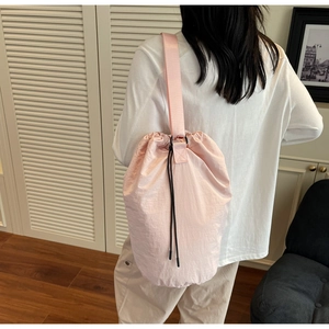Detailed view of lightweight pink drawstring bucket bag with textured nylon fabric and wide strap