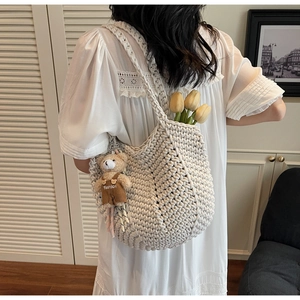 Detailed view of white woven crochet tote bag with cute bear charm and tulip props