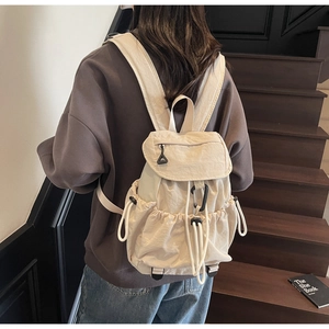 Detailed close-up of beige drawstring nylon backpack with flap and climbing rope buckles