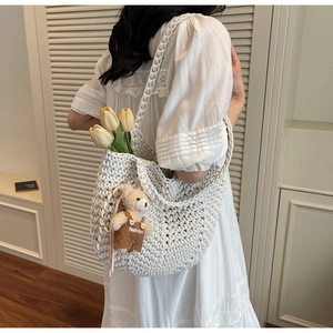 Detailed texture of white crochet hobo bag with a cute bear charm on a female model