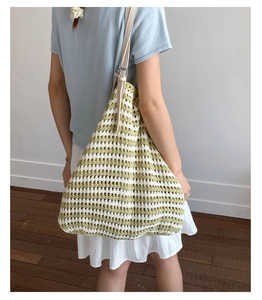 Detail of green and beige striped woven tote bag with adjustable cream leather strap