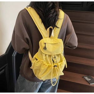 Close-up of a bright yellow nylon backpack with drawstring closure on a wooden stairs