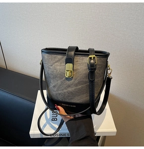 Detail of the gray denim bucket bag with gold hardware and leather trim details