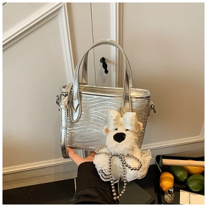 Close-up of silver wavy textured handbag with a cute plush dog pendant and crossbody strap