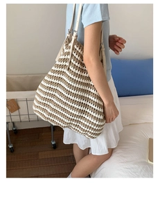 Close-up of a striped straw beach bag with bohemian fringe detail on shoulder strap