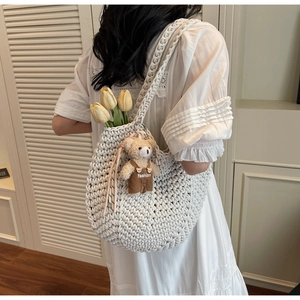 Detailed texture of white woven hobo bag with a cute bear charm in a cozy home setting