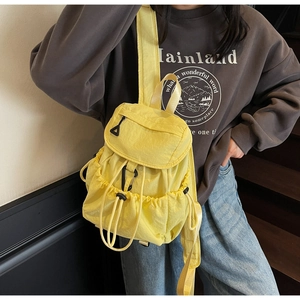 Dettaglio dello zaino in nylon giallo brillante con coulisse indossato da una modella