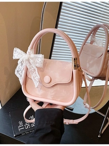 Pink mini crossbody bag with lace bow decoration shown in a mirror reflection