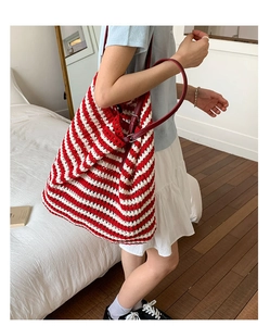 Detail of red and white striped knit tote bag with adjustable leather shoulder strap