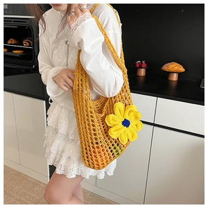 Close-up of yellow hollow knit shoulder bag with large floral detail and fruit inside