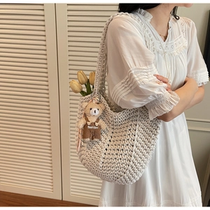 Detail of cream hand-woven hobo bag with cute brown bear plush charm and floral decor