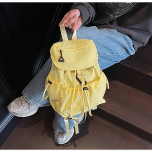 Dettaglio di uno zaino in nylon giallo con chiusura a coulisse e tirante nero