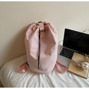 Detail of pink drawstring bucket bag made of waterproof nylon fabric on a soft bed