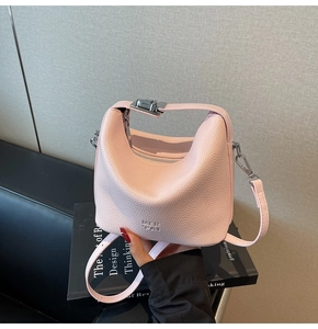 Detail of light pink lychee texture leather bucket bag with silver twist lock and strap