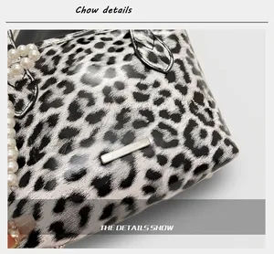 Detail of leopard print crossbody bag with silver metal plate and pearl chain decor