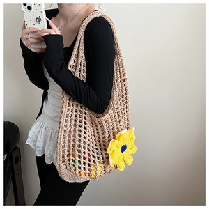 Detail of hand-woven beige mesh tote bag featuring a large yellow crochet flower accent