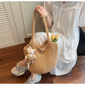 Detail of khaki hand-woven tote bag with cute bear charm and fashion tag detail