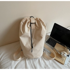 Close-up of beige drawstring bucket bag with waterproof nylon texture on a soft bed