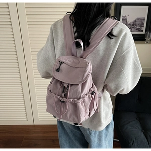 Vista dettagliata di uno zaino in nylon lilla con coulisse, patta e tasche laterali