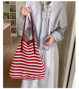 Detail of red and white striped straw tote with adjustable leather handles and tassels