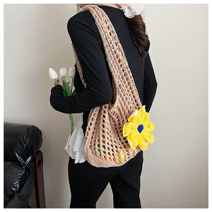 Detailed knit texture of beige crochet beach bag featuring large yellow flower charm