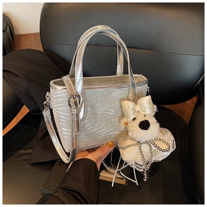 Detail of silver glitter handbag featuring water ripple texture and a cute plush charm